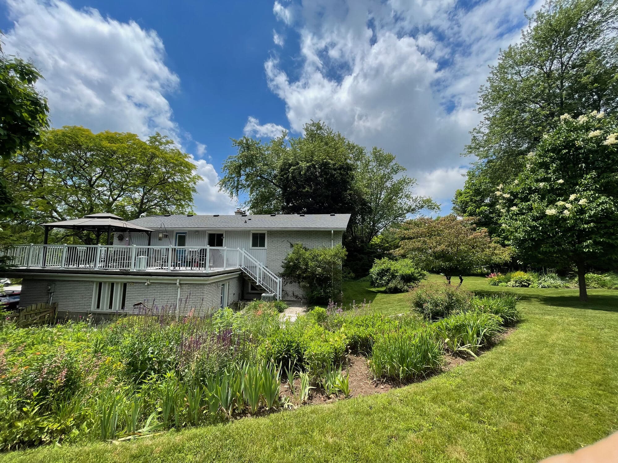 The back of the home with its deck and perennial gardens
